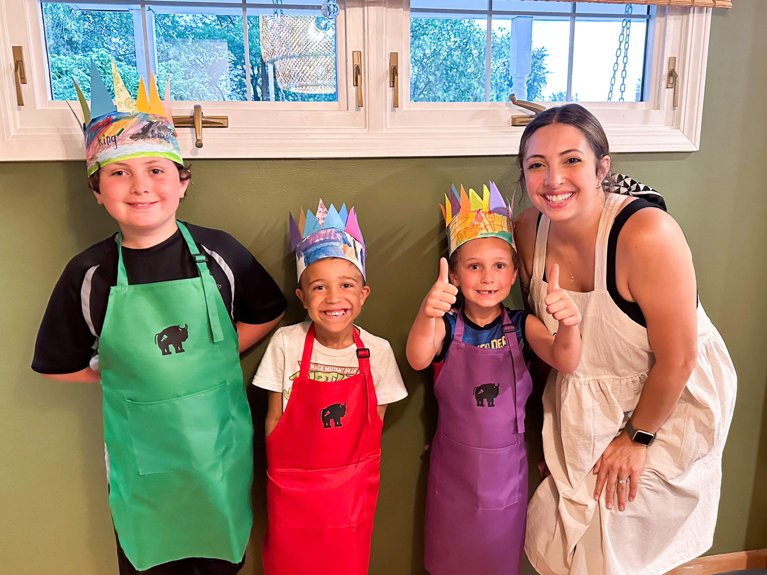 kids showing their completed paper crown craft at a birthday party