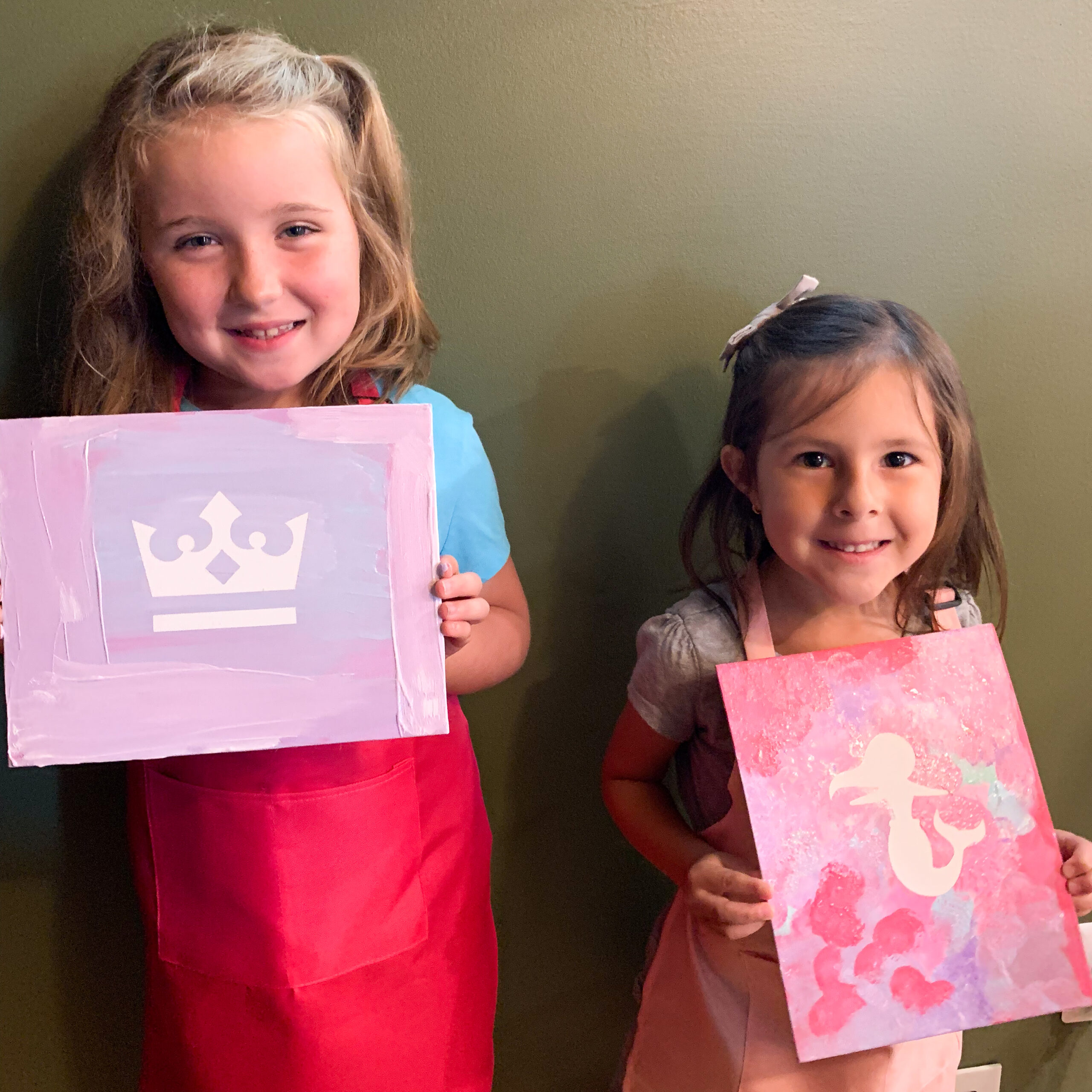two kids showing their artwork at a painting party